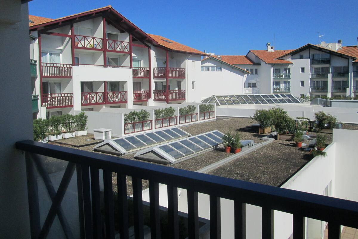 A multi-story building with balconies, solar panels, and potted plants.