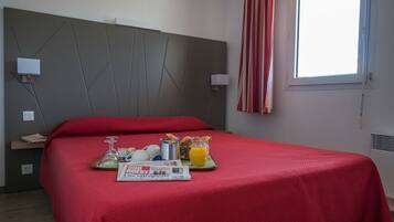 Habitación de hotel con cama, bandeja de desayuno y ventana con cortinas.