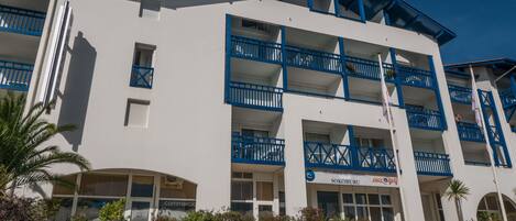 A multi-story hotel with blue balconies and a sign indicating it is a residence for tourism.