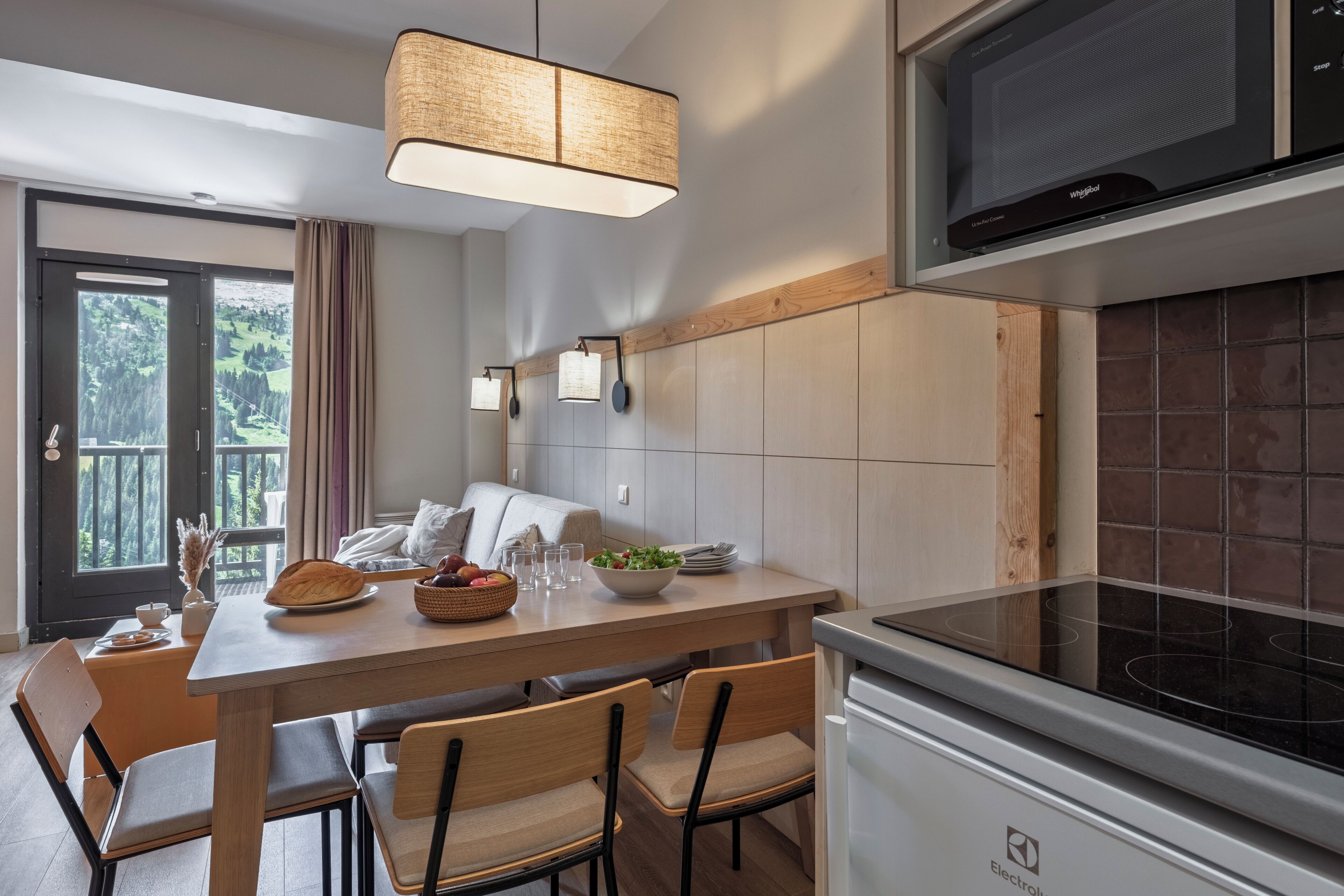 A modern kitchen with a microwave, stove, and dining area with chairs and a table.