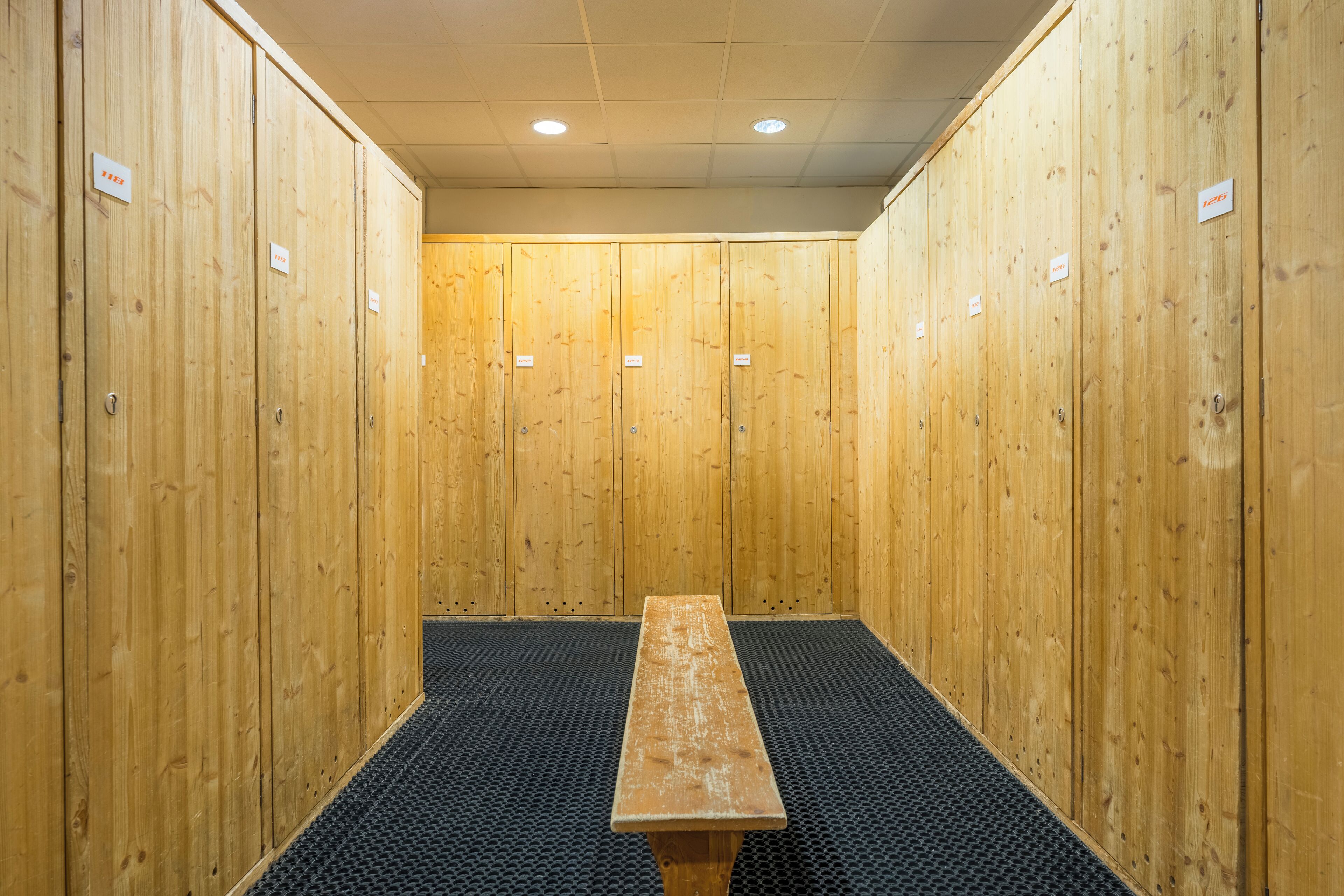 A row of wooden lockers with a bench in the center.