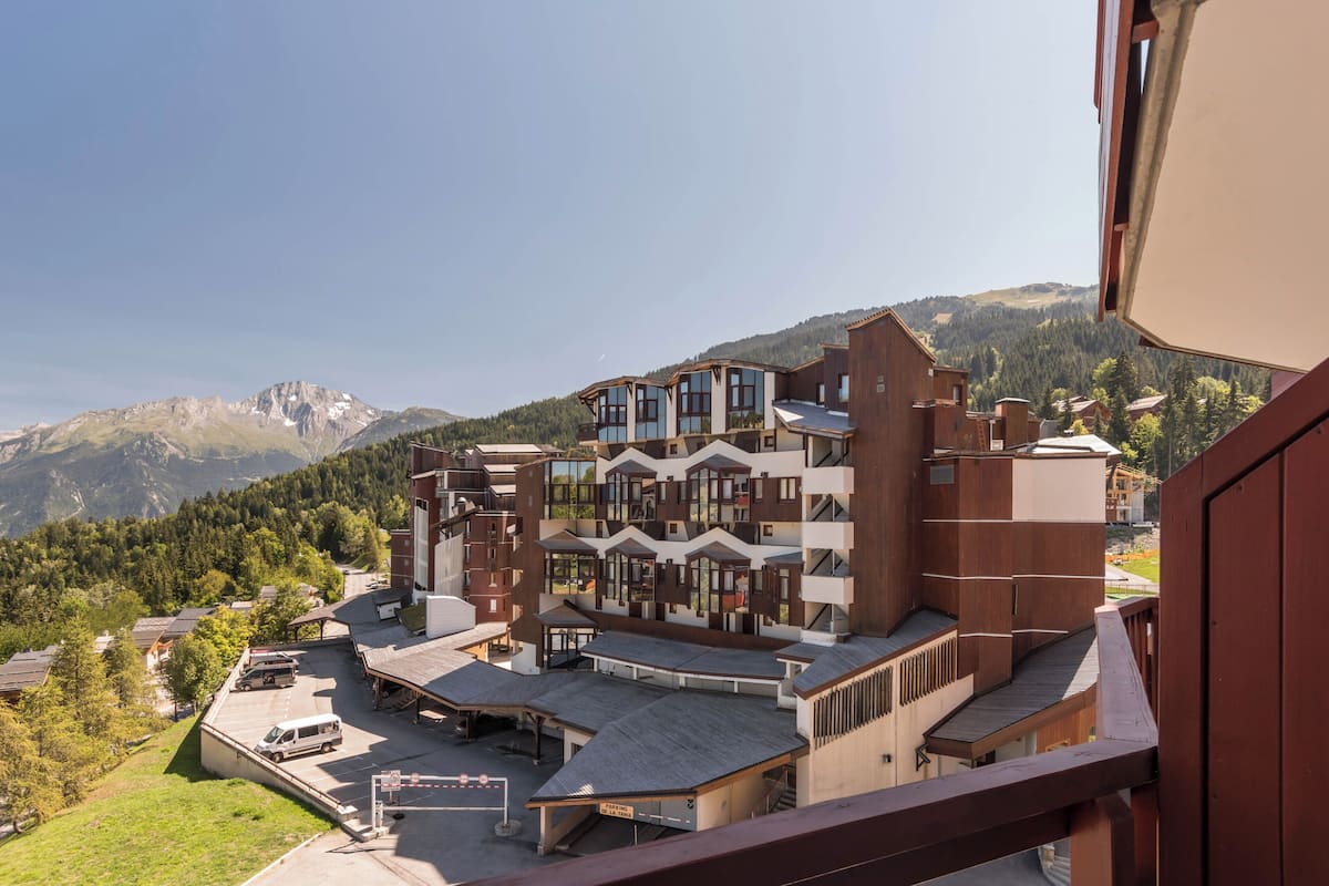 Ein mehrstöckiges Hotel mit moderner Architektur, mit Balkonen und einem Parkplatz.