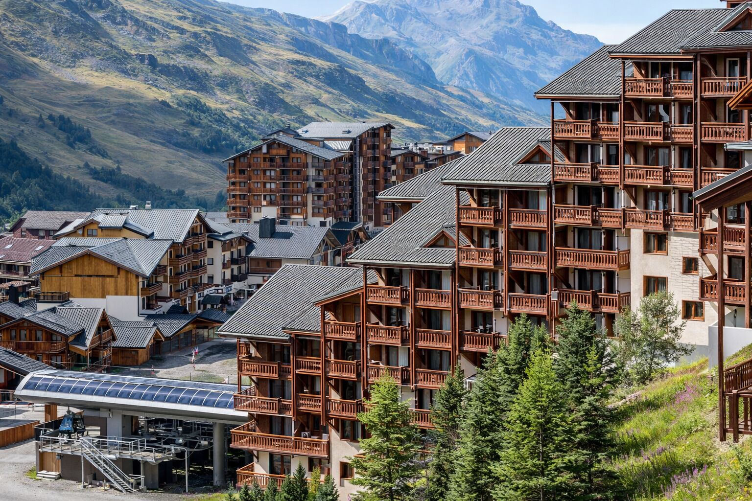 Un complejo turístico de montaña con edificios de madera, balcones y un conjunto de paneles solares.