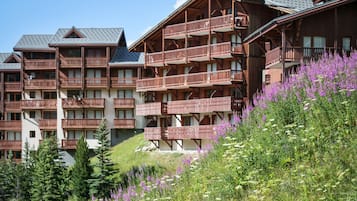 Un hotel de varios pisos con balcones, rodeado de exuberante follaje y flores silvestres.