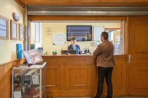 A reception desk with a wooden counter, a computer, and informational posters on the wall.