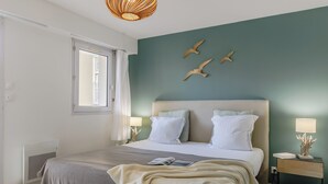 Un dormitorio con cama, lámparas de noche, ventana y decoración en la pared.