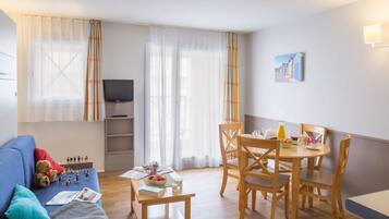 Relax in a cozy space with a sofa, dining table, and TV, perfect for unwinding and dining.