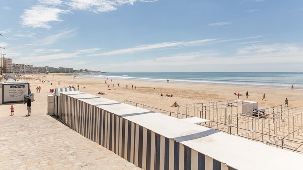 Una playa con un camino de piedra que lleva a un edificio con un letrero.