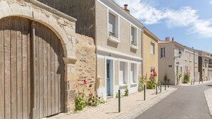 Una calle con arquitectura europea tradicional, con fachadas de piedra, persianas de madera y jardineras florales.
