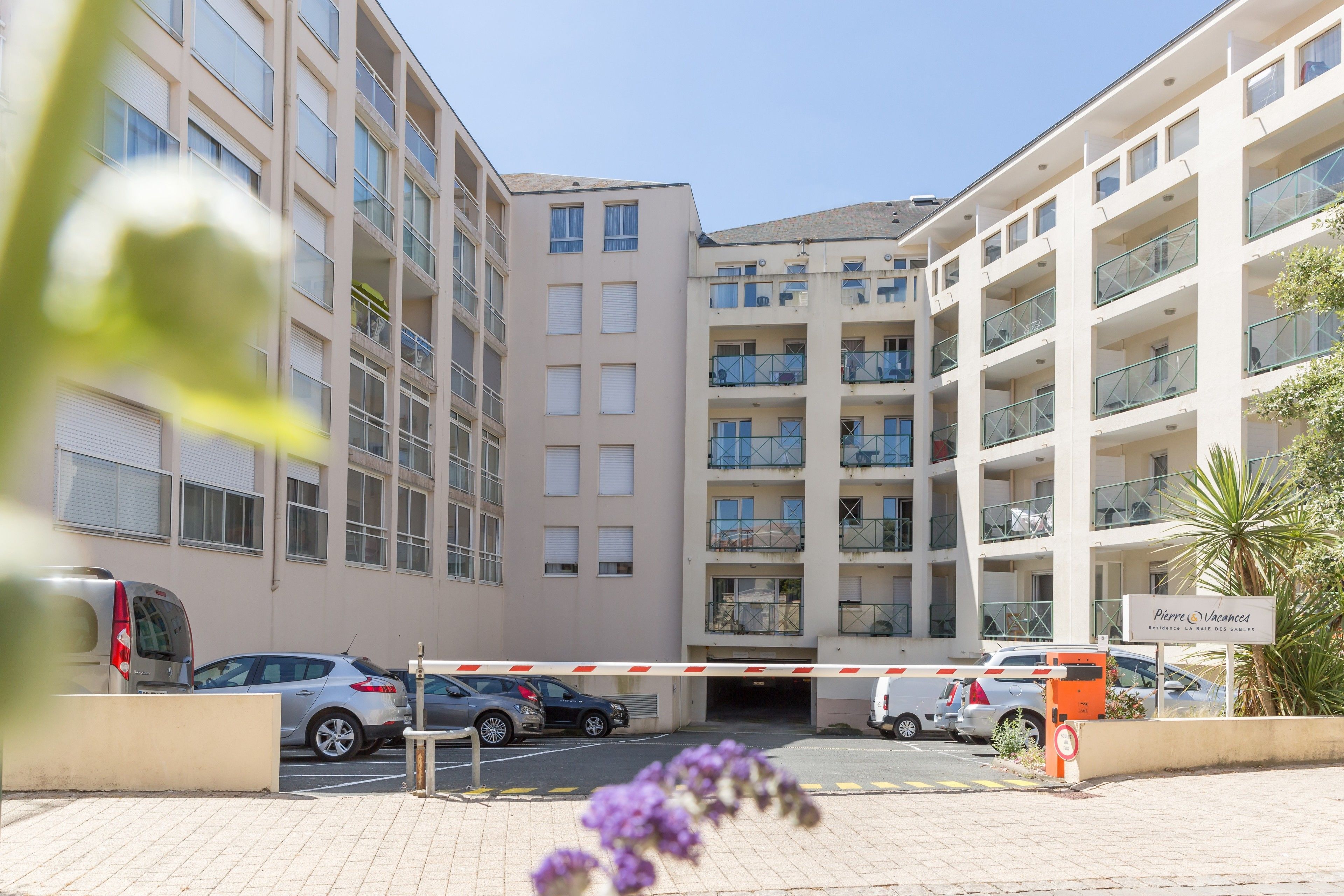 Un immeuble résidentiel à plusieurs étages, doté de balcons, d’un parking sécurisé et d’une enseigne indiquant un hôtel appelé « Pierre Vacanze ».