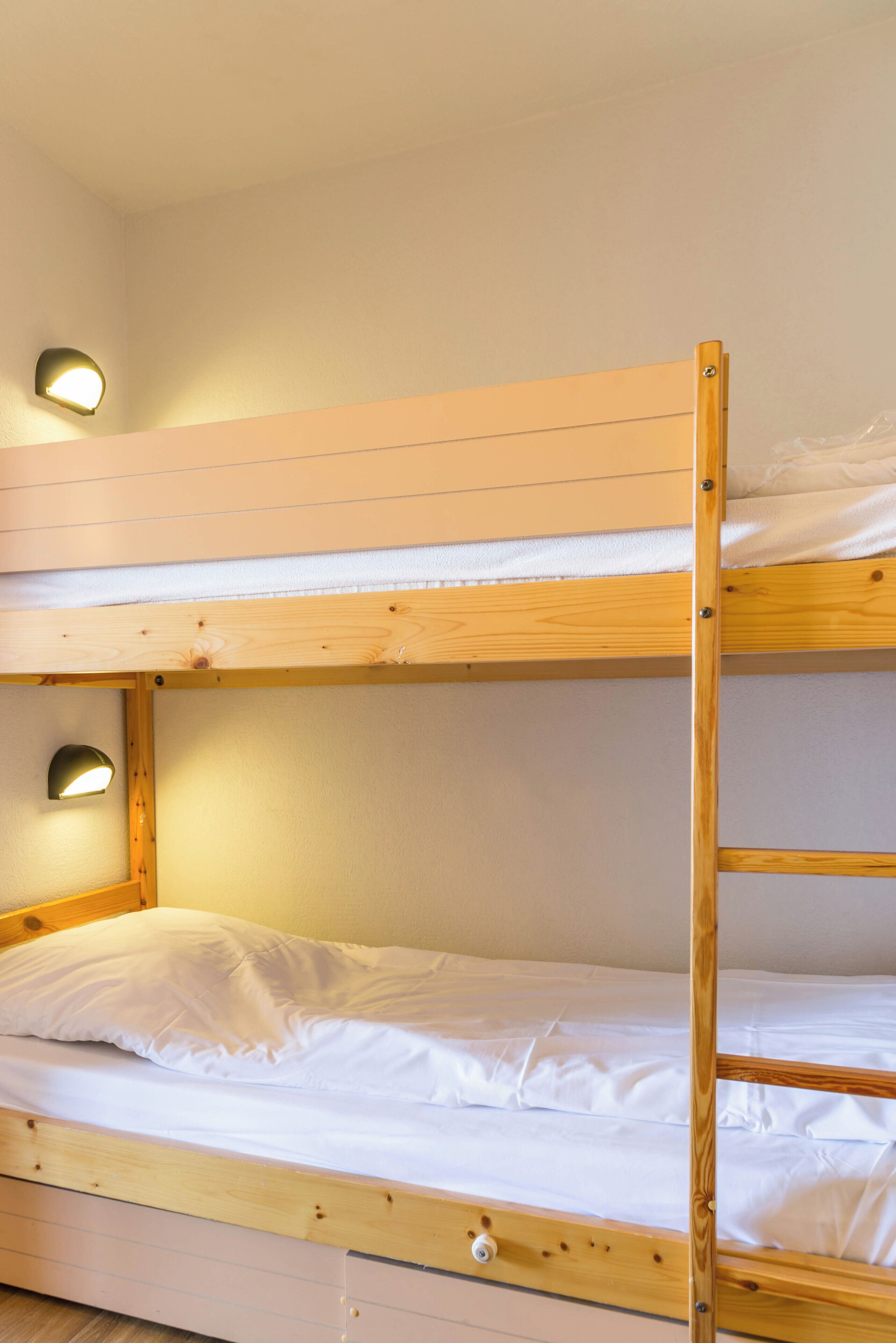Una cama litera con dos niveles, cada uno con una pequeña luz adosada a la pared.