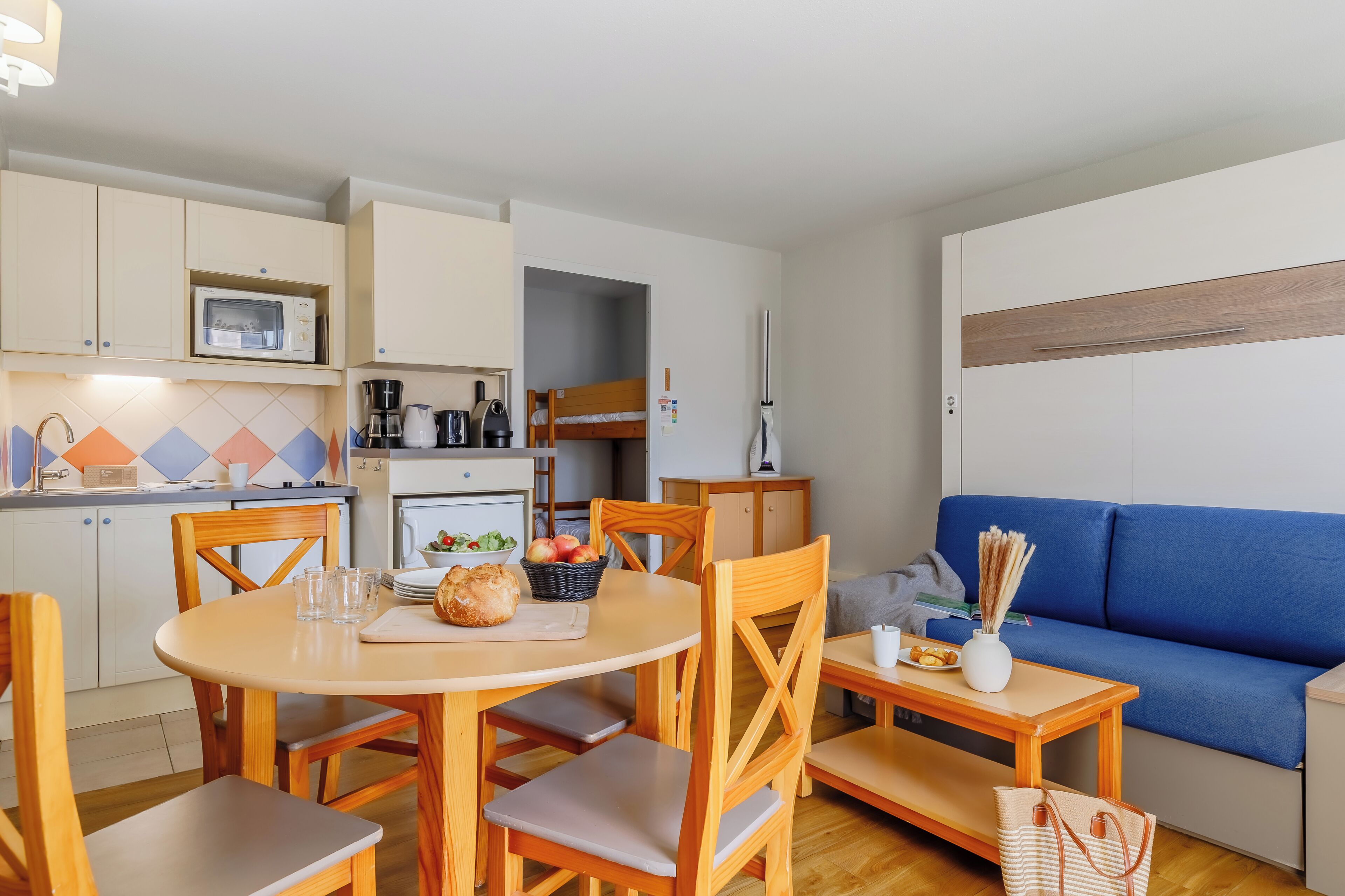 Un espacio habitable compacto con kitchenette, comedor y zona de estar.