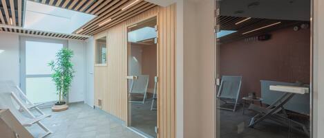 A modern waiting area with wooden slats on the ceiling, a potted plant, and a glass partition separating the space.