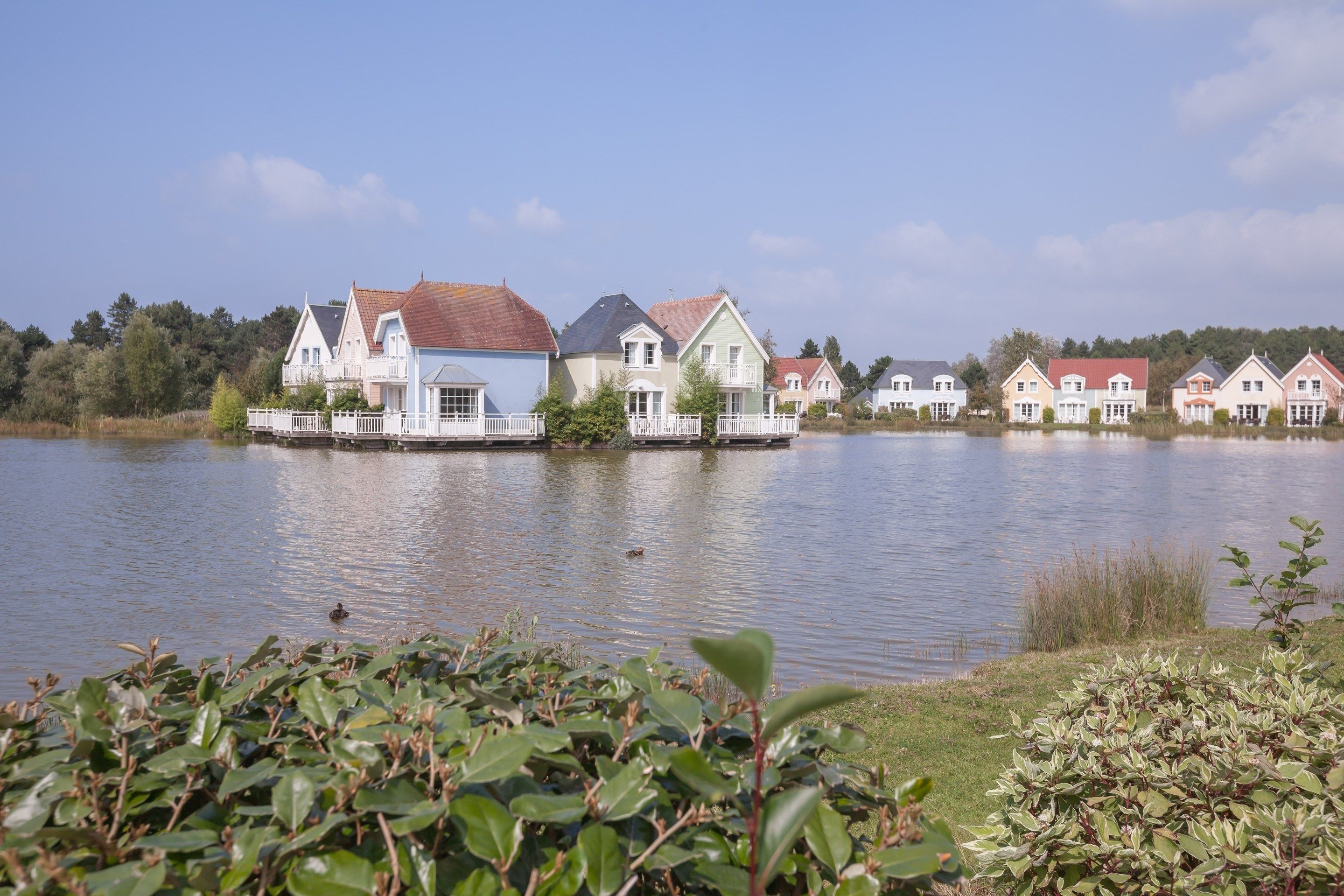 A row of houses by a lake with a clear sky.