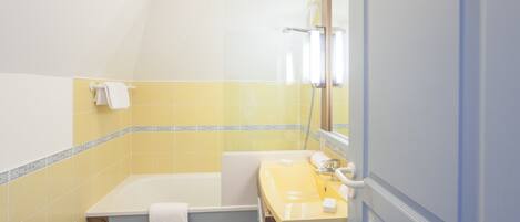 A bathroom with a bathtub, a sink, and a mirror.