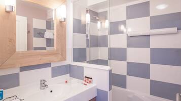 A bathroom with a white sink, a mirror, and a shower area.