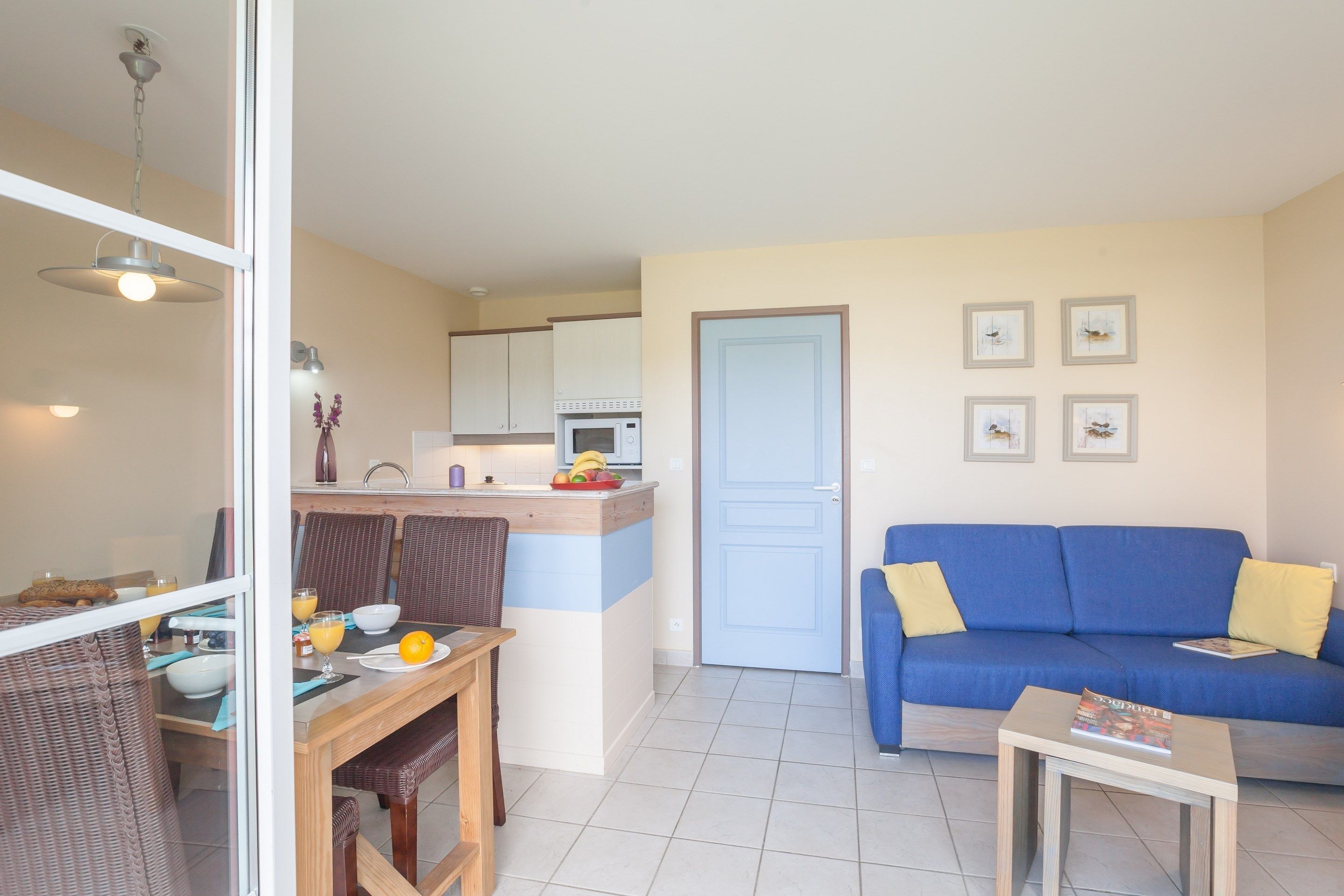 A compact living space with a dining area, kitchenette, and a blue sofa.