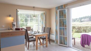 A dining area with a table and chairs, a kitchen counter, and a sliding glass door leading to an outdoor seating area.