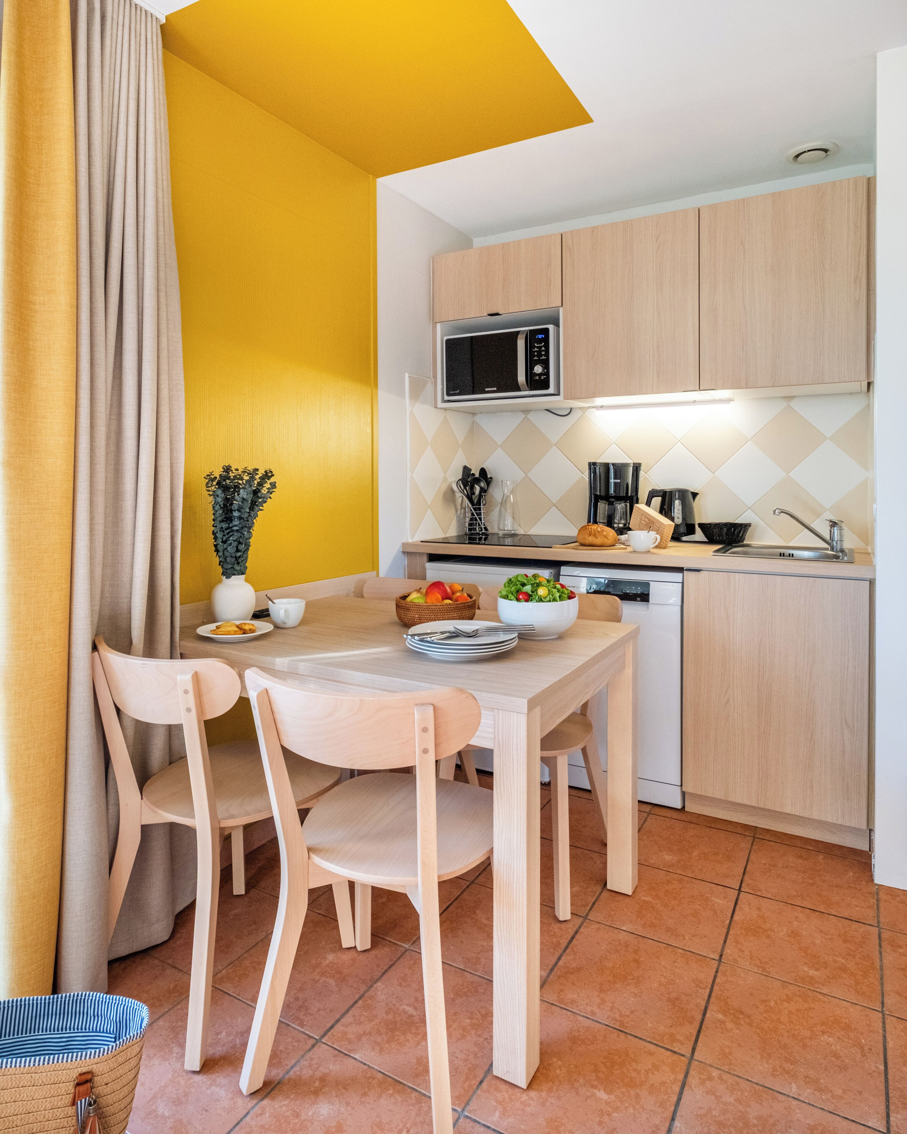 A compact kitchen with wooden cabinets, a microwave, and a dining area with a table and chairs.
