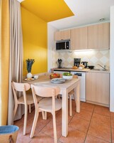 Una cocina compacta con armarios de madera, un microondas y un comedor con mesa y sillas.