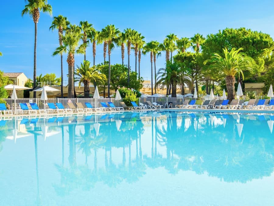 Una piscina al aire libre de temporada, sombrillas, tumbonas