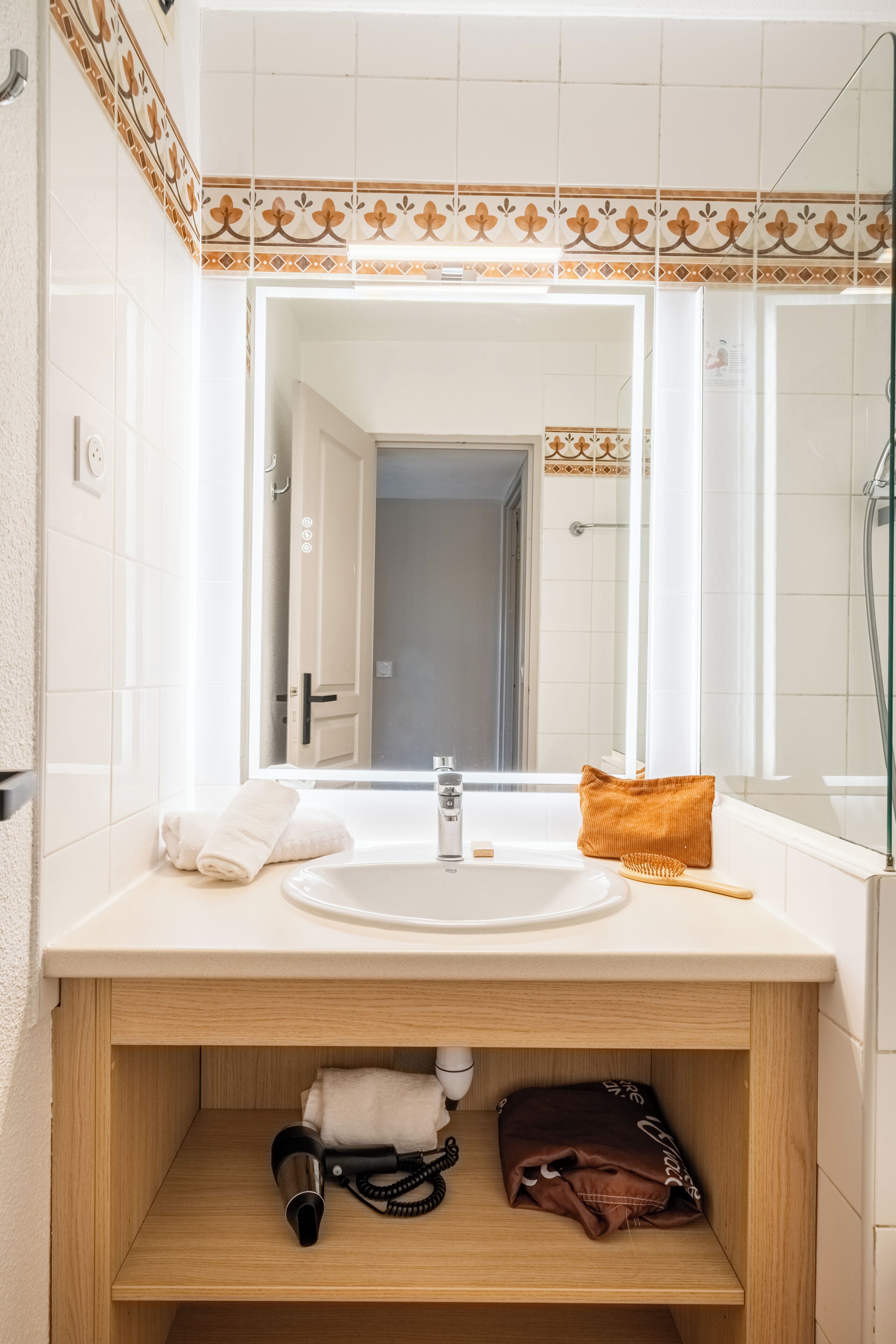Une salle de bain équipée d’un lavabo, d’un miroir et d’un espace pour ranger les serviettes.