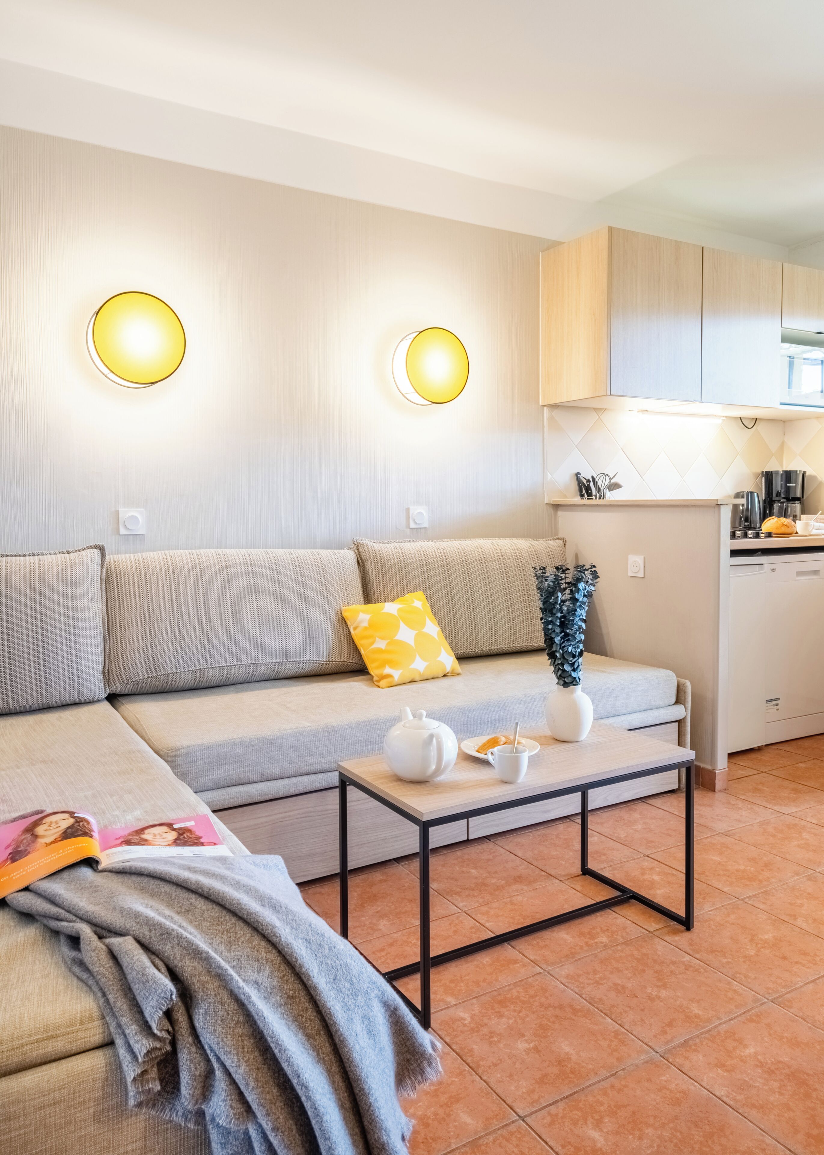A modern living room with a sofa, coffee table, and a kitchen area in the background.