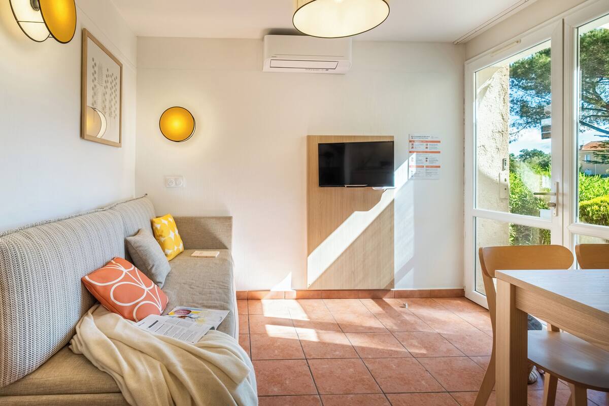 Ein Wohnzimmer mit Sofa, Fernseher, Treppe und Essbereich.