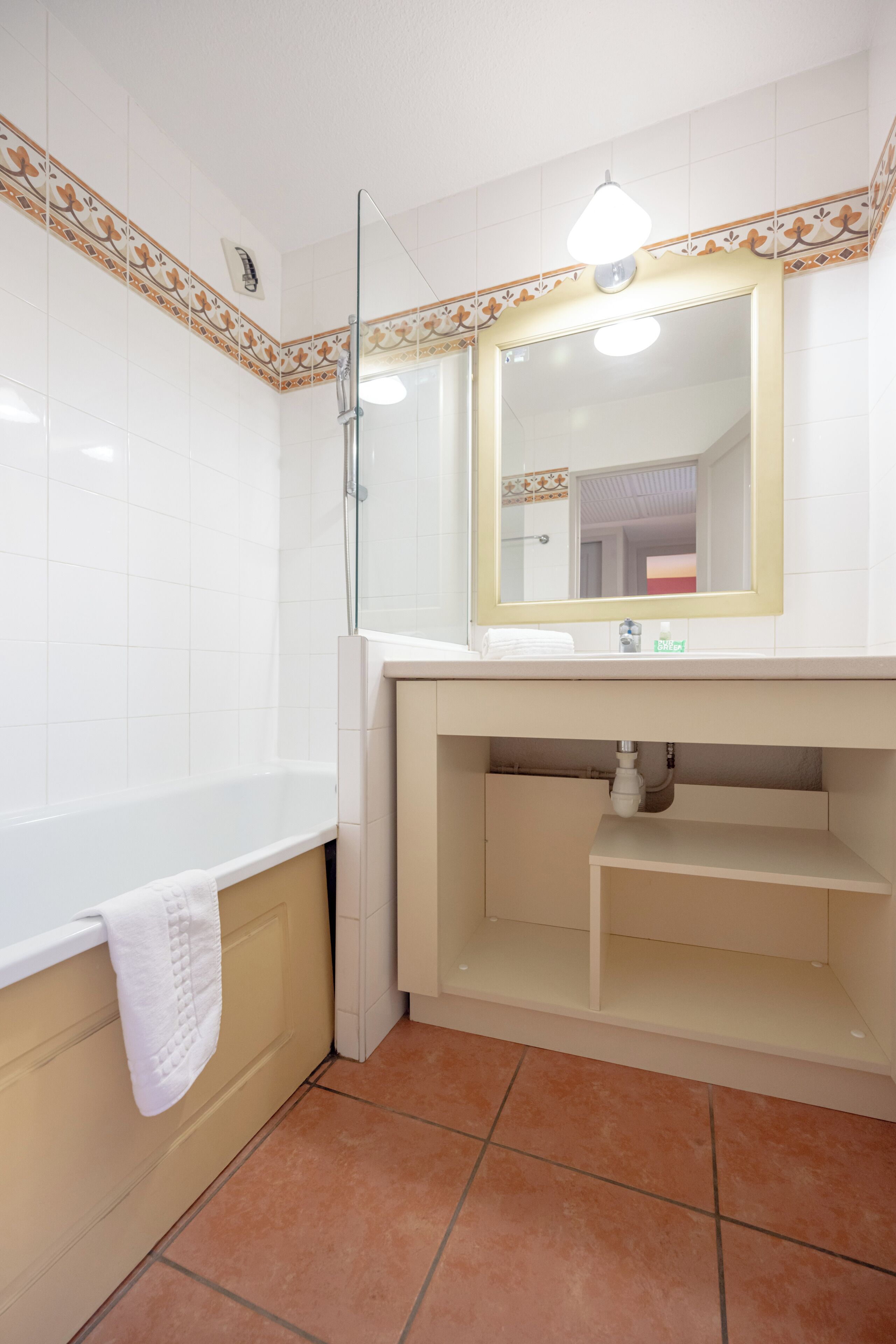 A bathroom with a bathtub, a mirror, and a sink.