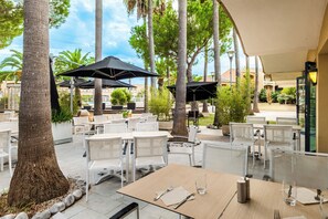 An outdoor seating area with tables and chairs, umbrellas, and trees. - Pierre & Vacances Residence Cannes Mandelieu (Mandelieu-La-Napoule)