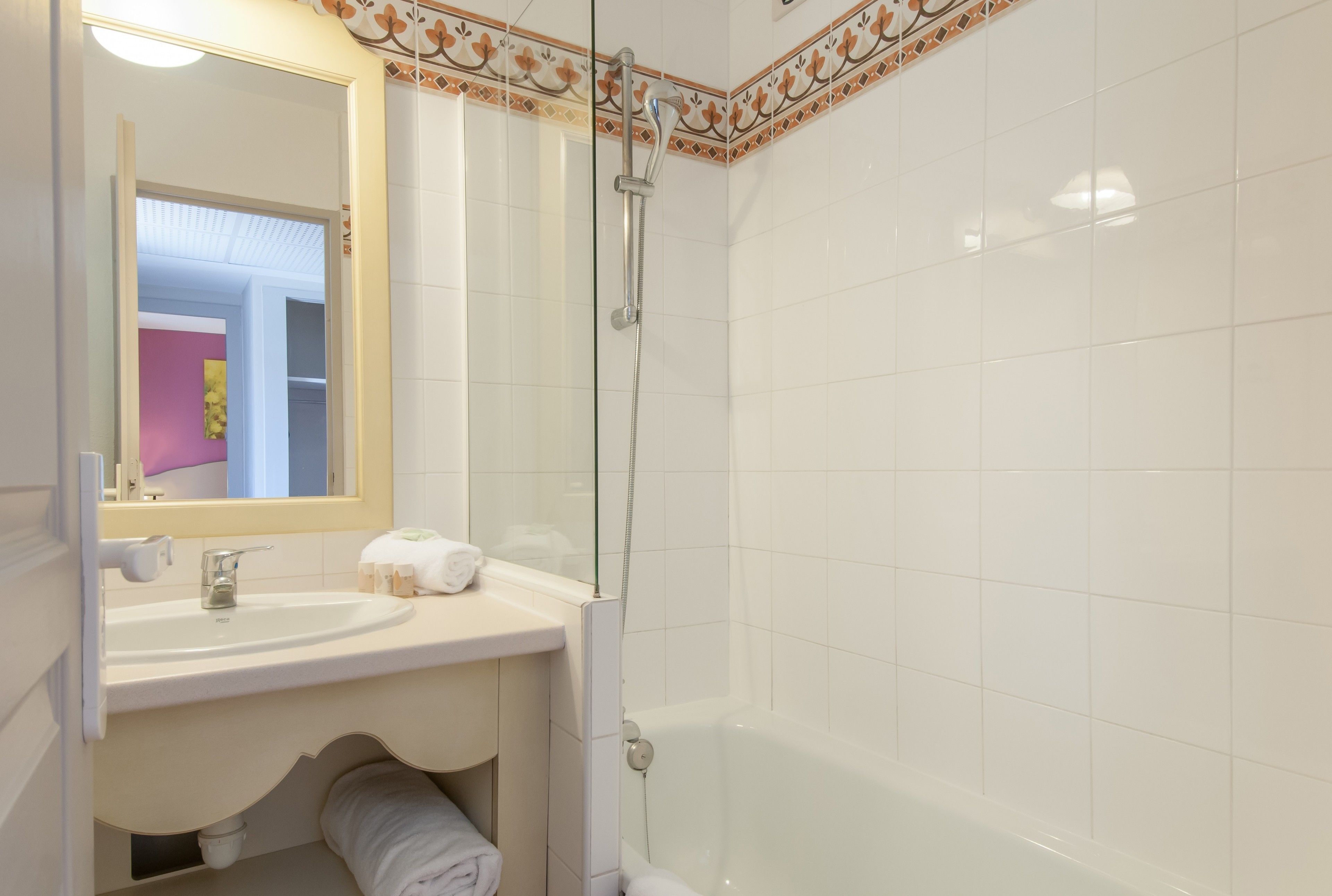 A bathroom with a white sink, mirror, and shower.