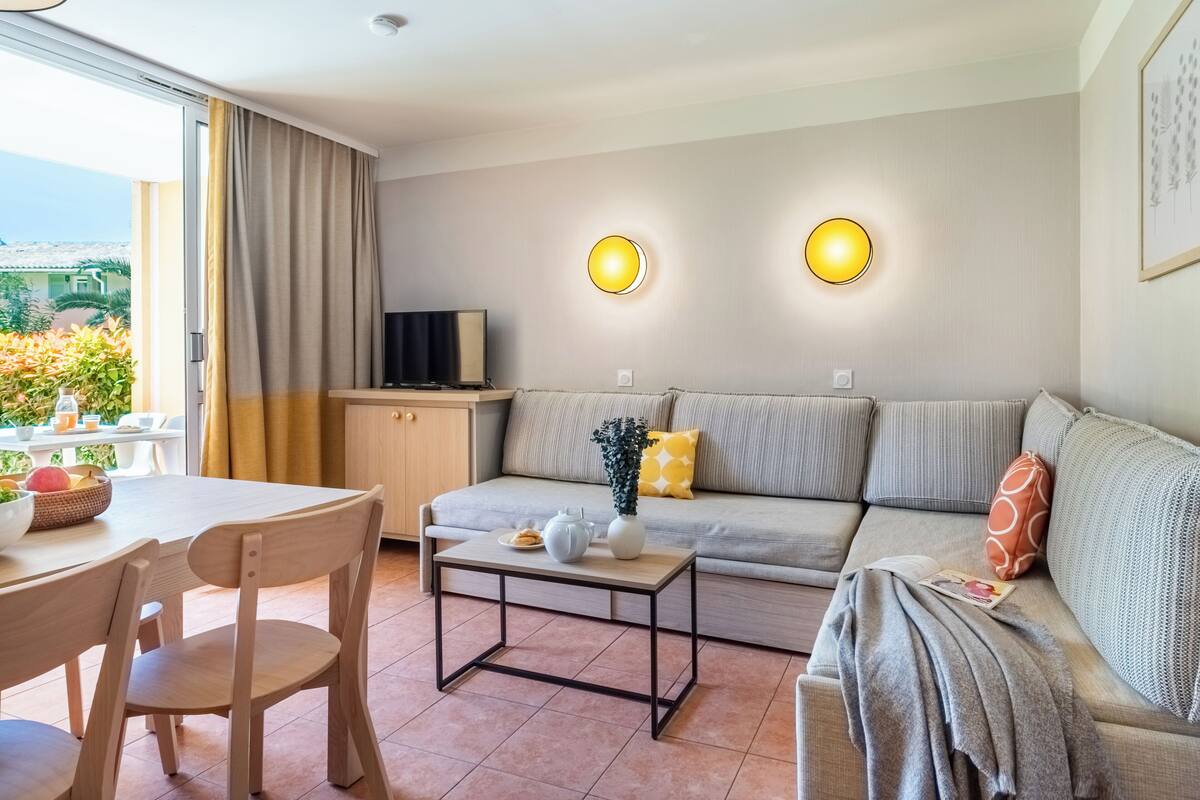 Ein modernes Wohnzimmer mit einer Couch, einem Couchtisch und einem Fernseher auf einem Schrank.