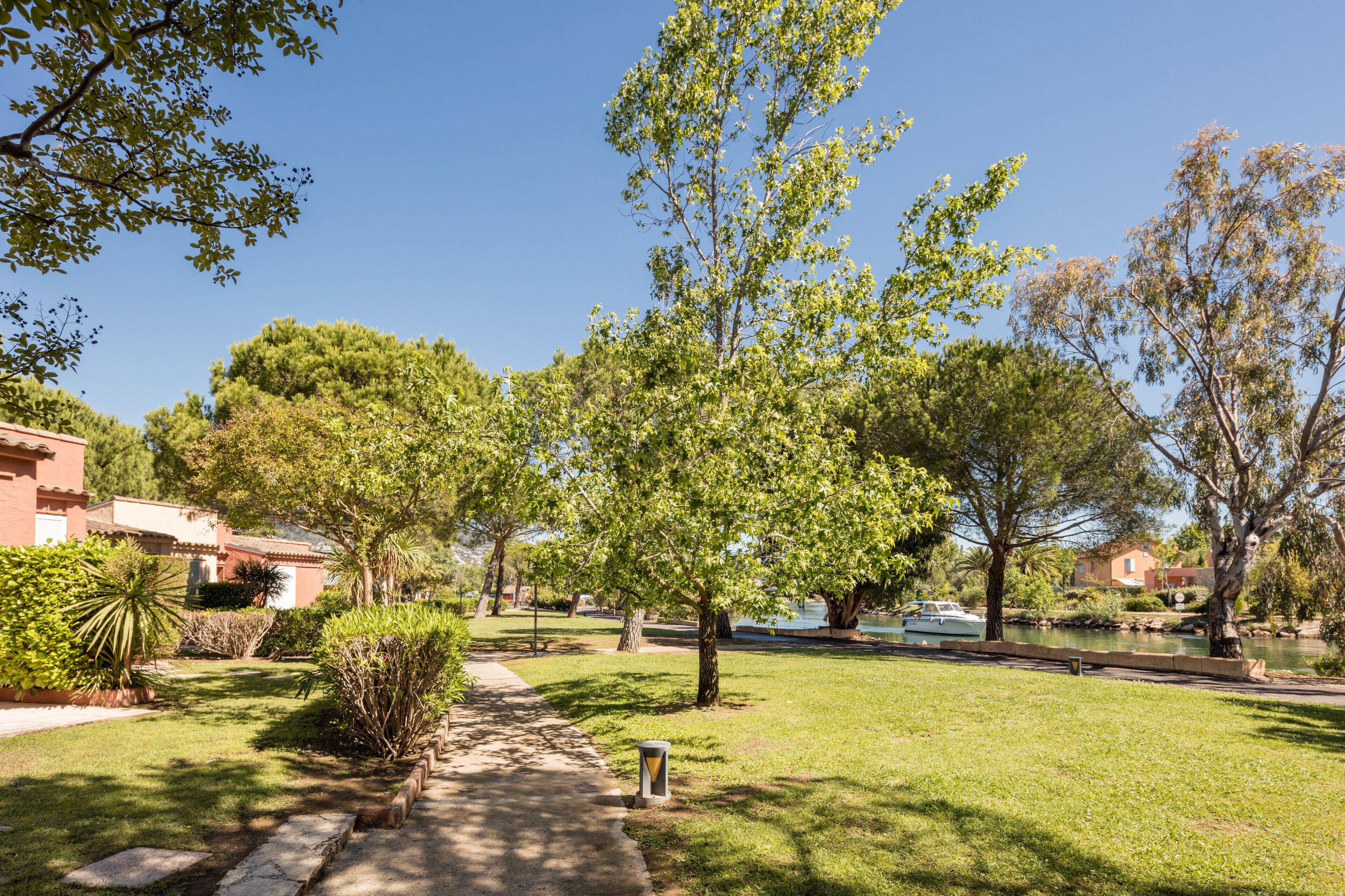 A pathway leading to a grassy area with trees and a body of water.