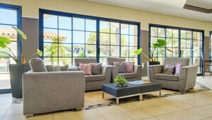 A spacious living area with large windows, grey sofas, and a central coffee table. - Pierre & Vacances Residence Cannes Mandelieu (Mandelieu-La-Napoule)