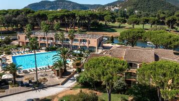 Un hotel con piscina, diversi edifici e vegetazione circostante.