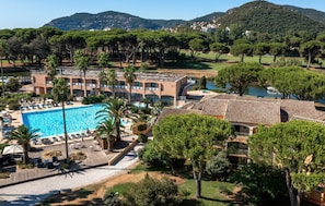 Et hotel med swimmingpool, flere bygninger og grøn bevoksning omkring.
