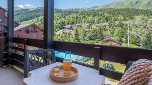 A balcony with a table, a pitcher, and glasses of a beverage. - Résidence Pierre & Vacances Les Ravines (Les Allues)