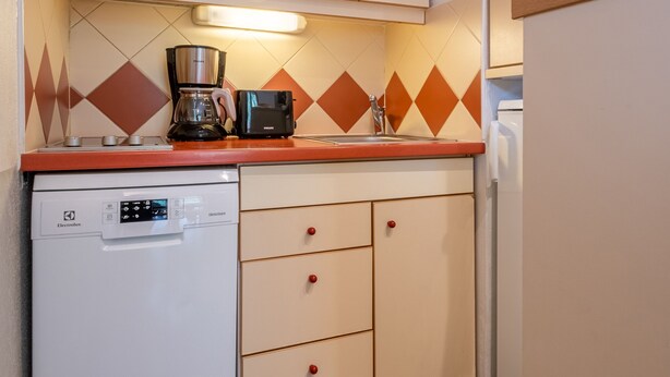 A compact kitchen with a microwave, coffee maker, and dishwasher.