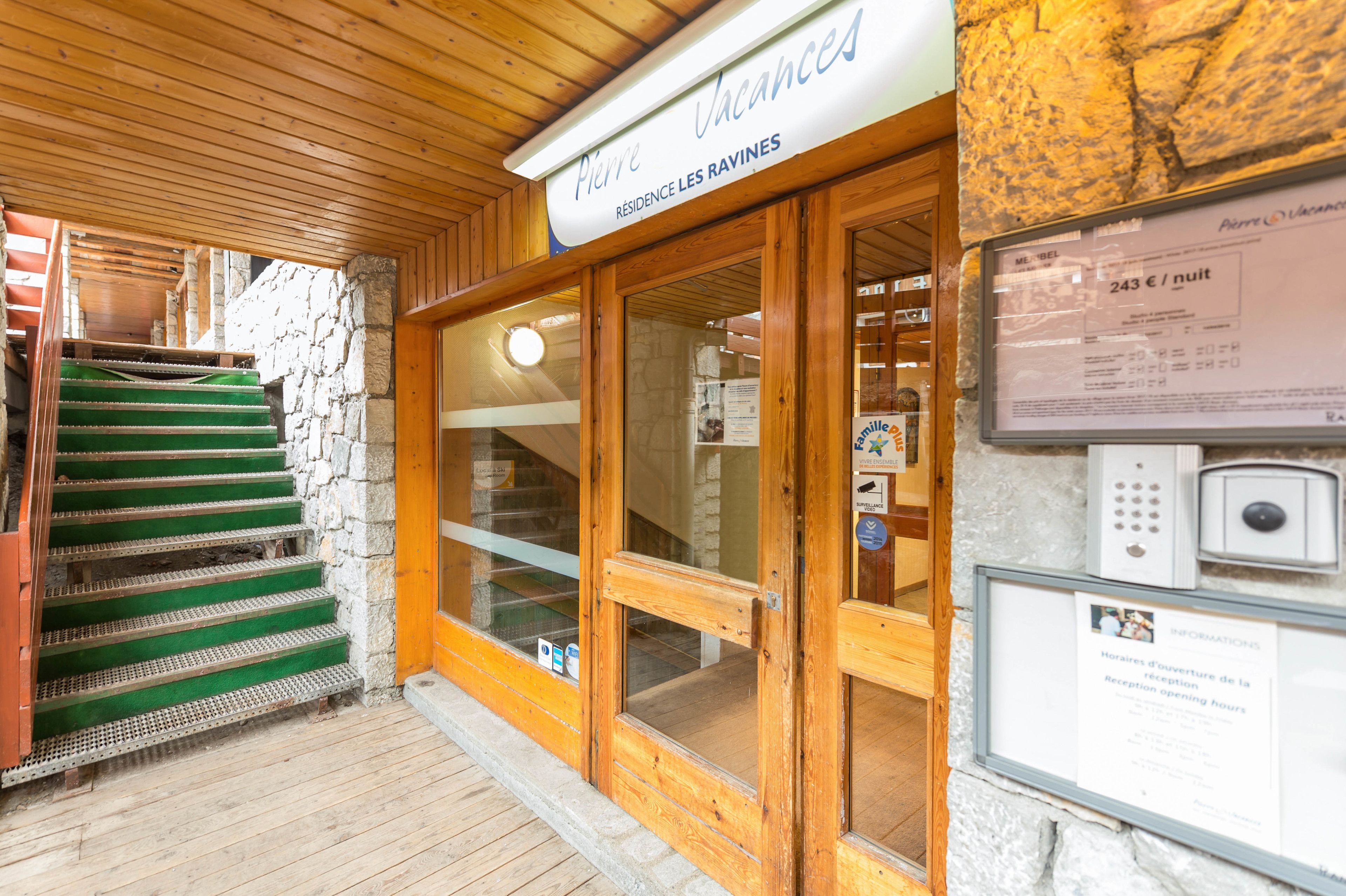 A hotel entrance with a wooden staircase, stone walls, and a sign indicating room rates.