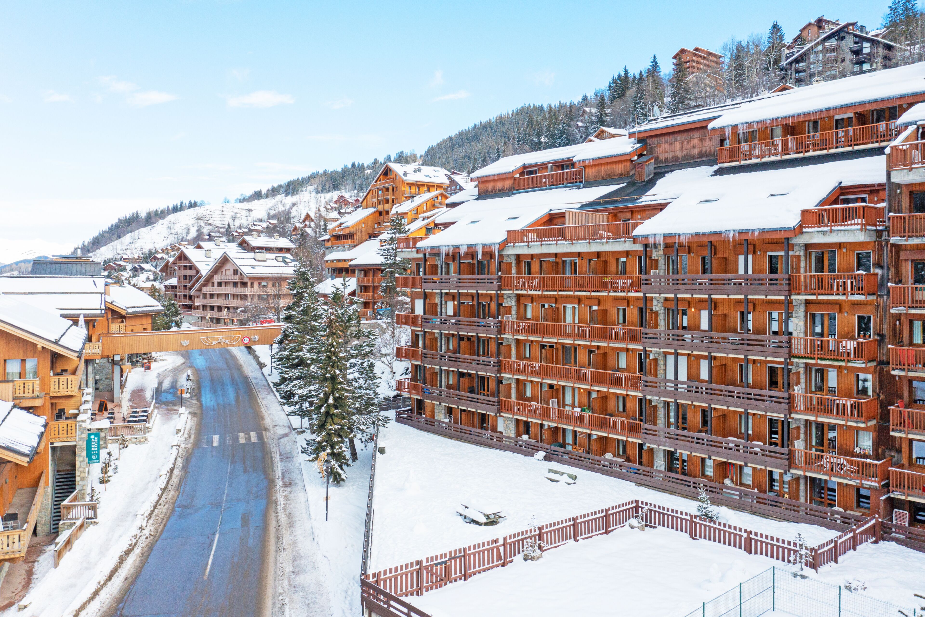 A snow-covered town with wooden buildings and a clear road.