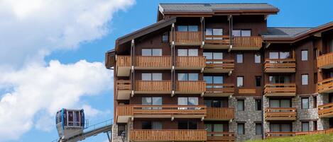 Un hotel de varios pisos con balcones, un teleférico y fachada de piedra.