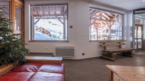 A cozy interior with large windows, wooden benches, and a red cushioned seating area.