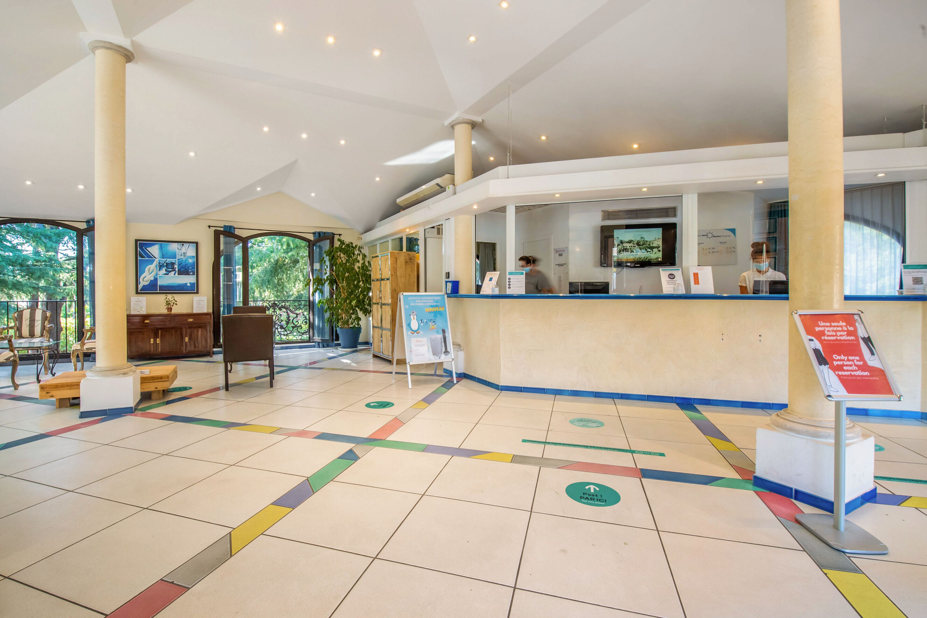 Un hall espacioso con mostrador de recepción, zona de estar y señalización en el suelo.
