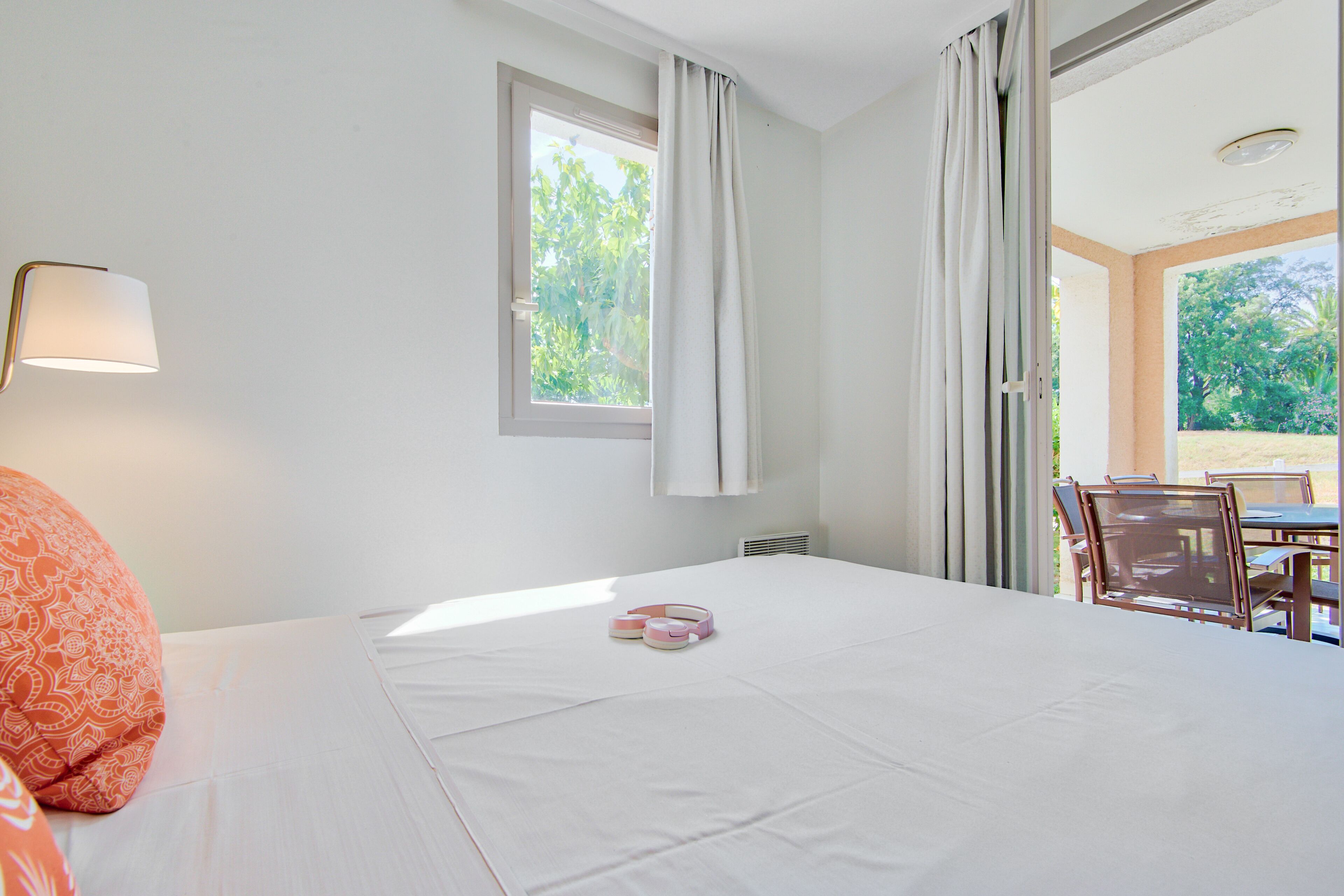 A hotel room with a bed, a window, a table, and chairs.