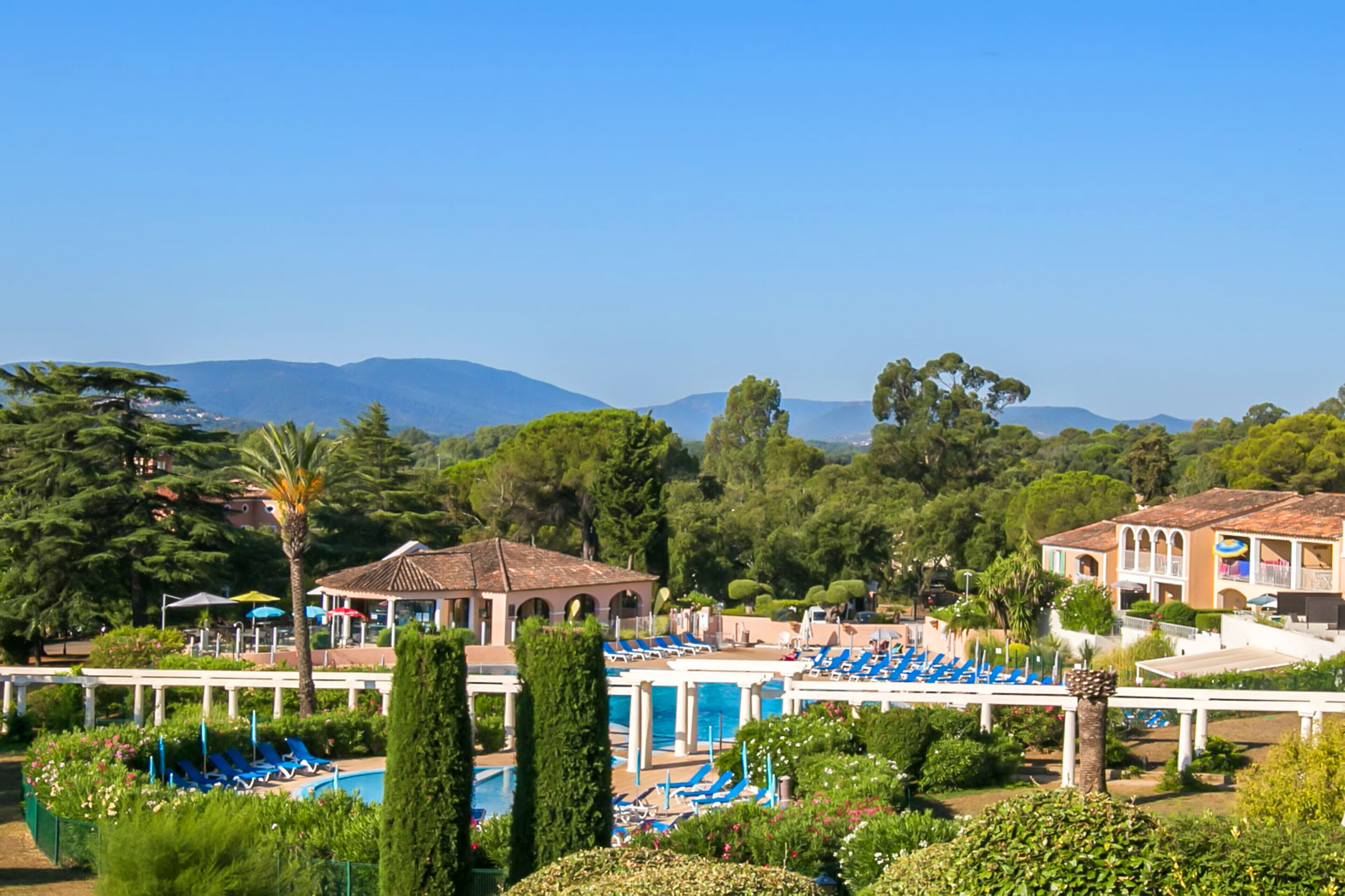 A resort with a pool area, lounge chairs, and a view of mountains.