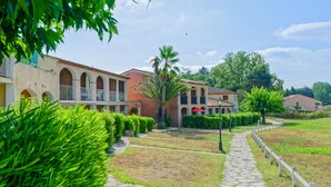 Un patio con un sendero de piedra, setos cuidadosamente recortados y una hilera de edificios con ventanas arqueadas y balcones.