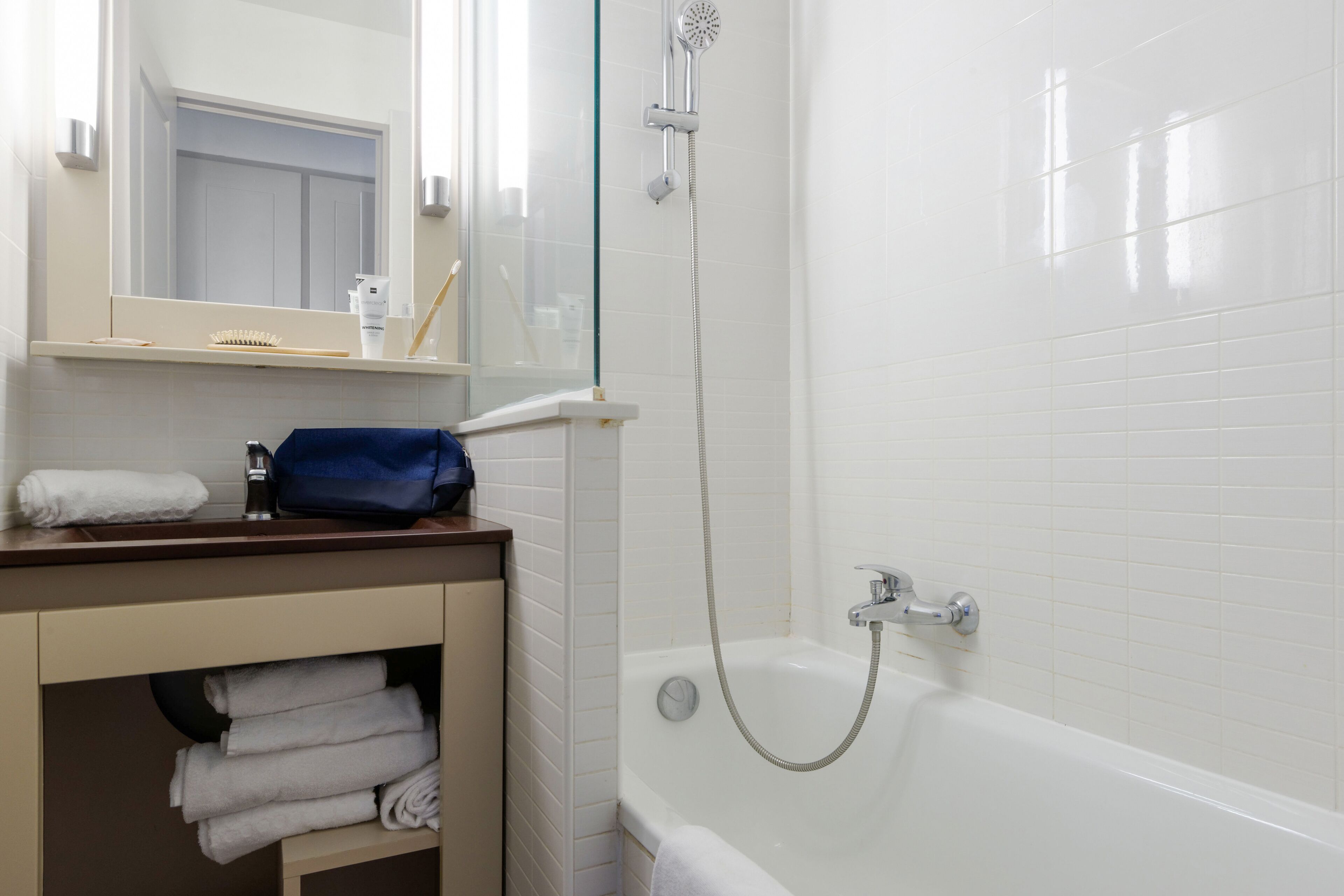 Un baño con una bañera blanca, ducha con cerramiento de vidrio y espejo sobre el lavamanos.