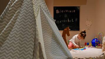 Children can play and explore in this welcoming space with a large tent-like structure, chalkboard, and toys.