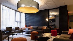 Un espace de détente moderne comprenant un canapé, des fauteuils, des poufs et une table basse.
