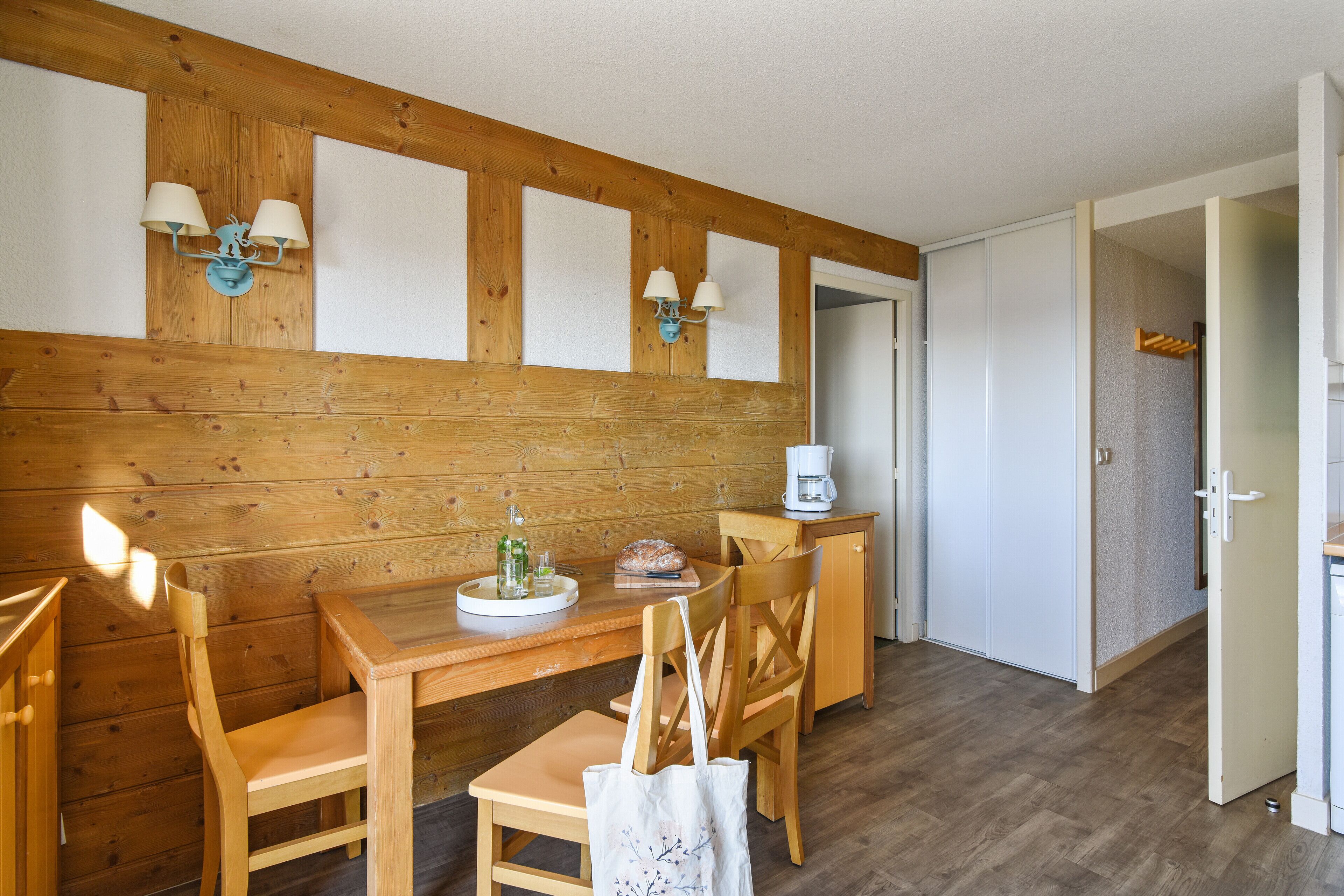 Een houten eethoek met een tafel, stoelen en een koffieapparaat.